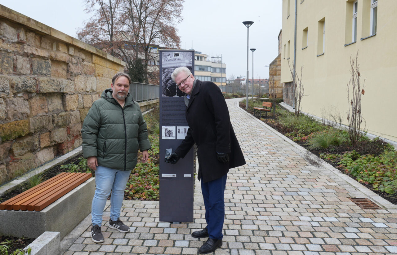 Zwei Männer präsentieren auf einem gepflasterten Weg eine Infostele. | Foto: Stadt Bayreuth