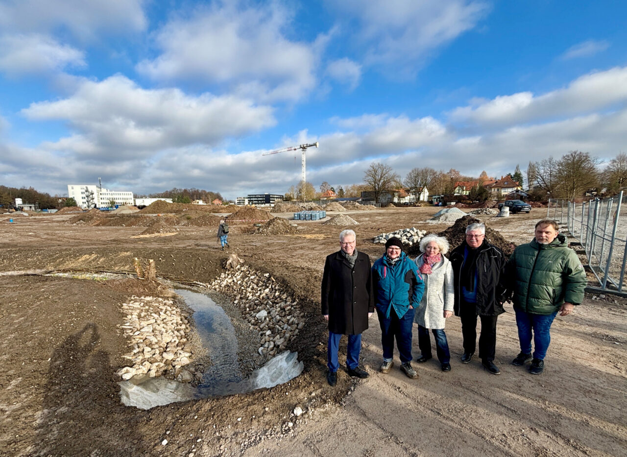 Drei Männer und zwei Frauen stehen auf einem Baugelände an einem Bachlauf. | Foto: Stadt Bayreuth