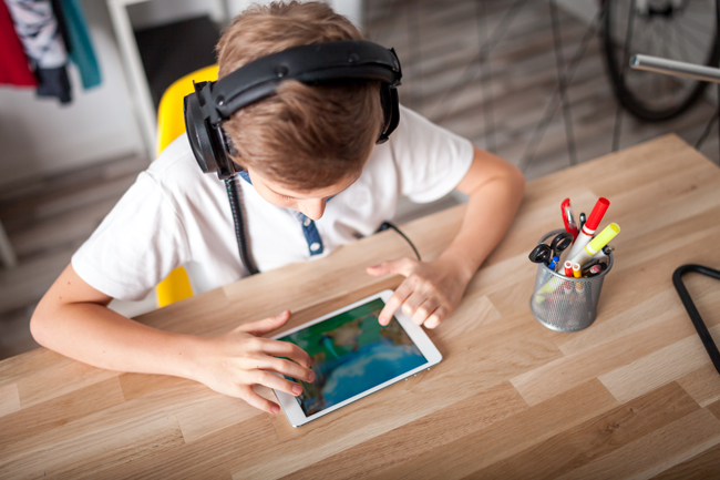 Ein Jugendlicher mit Kopfhörern benutzt ein Tablet. Foto: Adobe Stock