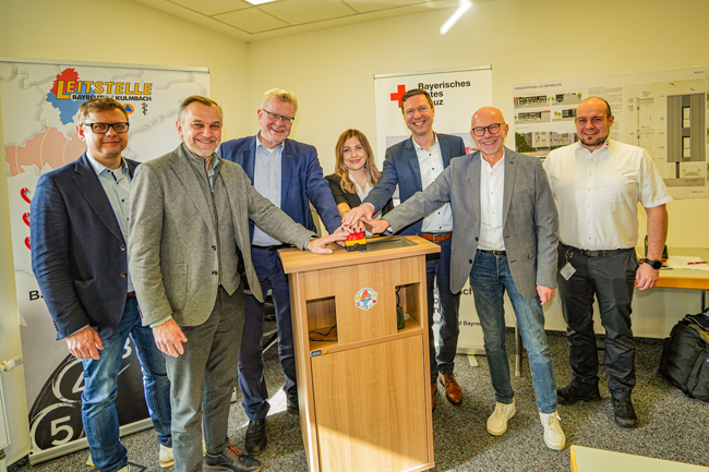 Bei einem Medientermin gaben die Verantwortlichen den Startschuss für das etwa 4,5 Millionen Euro teure Projekt mit einem symbolischen Druck auf einen roten Alarmierungsknopf. Unser Bild zeigt (v. li.) den Kreisgeschäftsführer des BRK Bayreuth, Markus Ruckdeschel, den Leiter des Amtes für Öffentliche Sicherheit am Landratsamt Kulmbach, Oliver Hempfling, ZRF-Vorsitzenden und Oberbürgermeister Thomas Ebersberger, die Direktorin der AOK Bayreuth-Kulmbach, Melanie Heinlein-Lodes, Landrat Florian Wiedemann, ZRF-Geschäftsführer Harald Burkhardt sowie Dr. Christopher Häfner, Leitstellenleiter der ILS Bayreuth/Kulmbach. Foto: Stadt Bayreuth