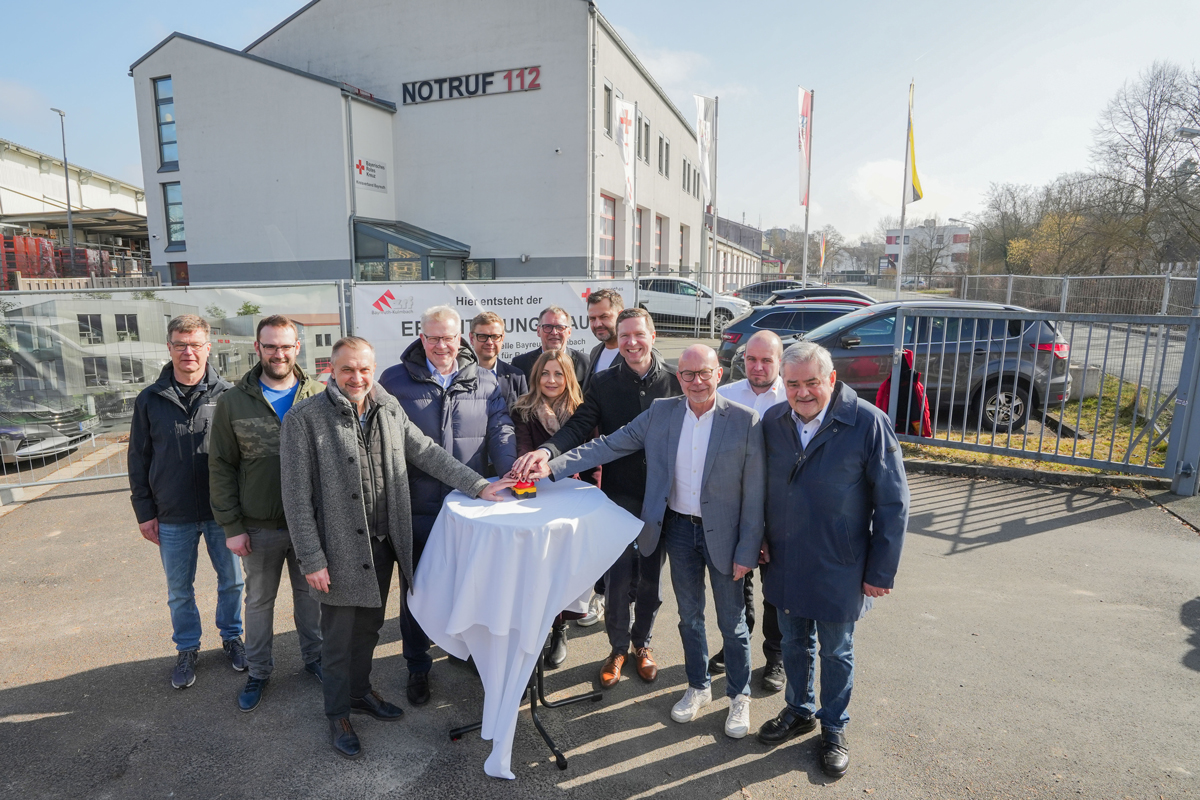 Mehrere Personen drücken auf einen roten Alarmierungsknopf. Foto: Stadt Bayreuth