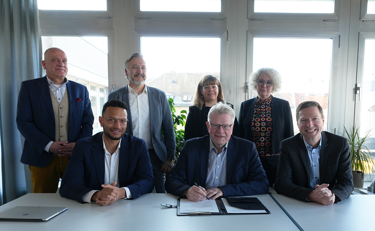Bei der Vertragsunterzeichnung freuen sich: Bernhard Sippel von der städtischen Wirtschaftsförderung, Dimitry McDuffie, Manuel Peetz vom städtischen Hochbauamt, Wirtschaftsreferentin Eva Christina Bär, Oberbürgermeister Thomas Ebersberger, Baureferentin Urte Kelm und Landrat Florian Wiedemann.