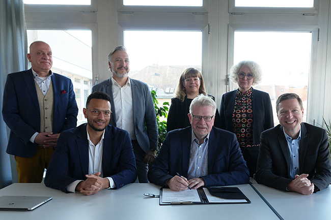 Bei der Vertragsunterzeichnung freuen sich: Bernhard Sippel von der städtischen Wirtschaftsförderung, Dimitry McDuffie, Manuel Peetz vom städtischen Hochbauamt, Wirtschaftsreferentin Eva Christina Bär, Oberbürgermeister Thomas Ebersberger, Baureferentin Urte Kelm und Landrat Florian Wiedemann.