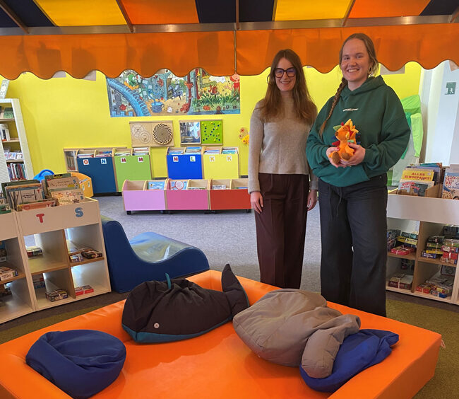 Kathrin Weishäupl (li.) von Miss Smarthead GmbH übergibt das Kuschelnest an Kinderbibliotheksleitung Alexandra Warzecha. Foto: RW21 Stadtbibliothek