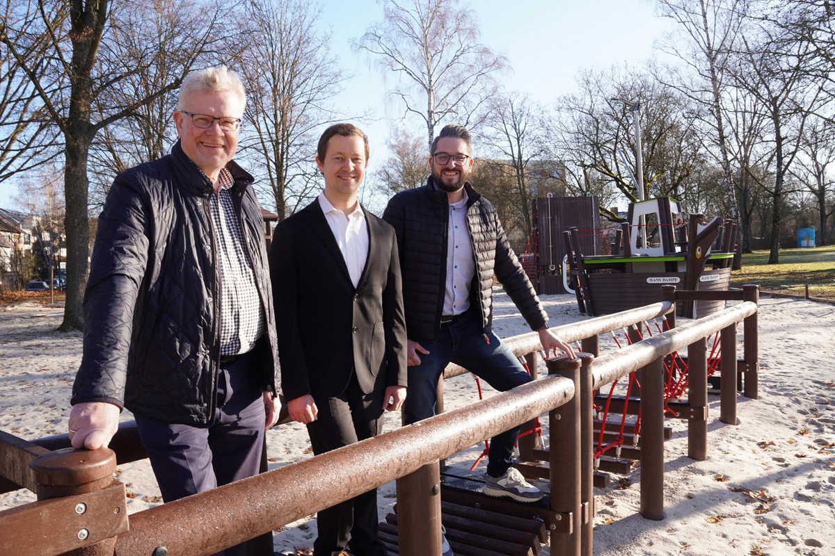 Drei Männer stehen auf einem Spielplatz an einer Holzbarriere. | Foto: Stadtwerke Bayreuth