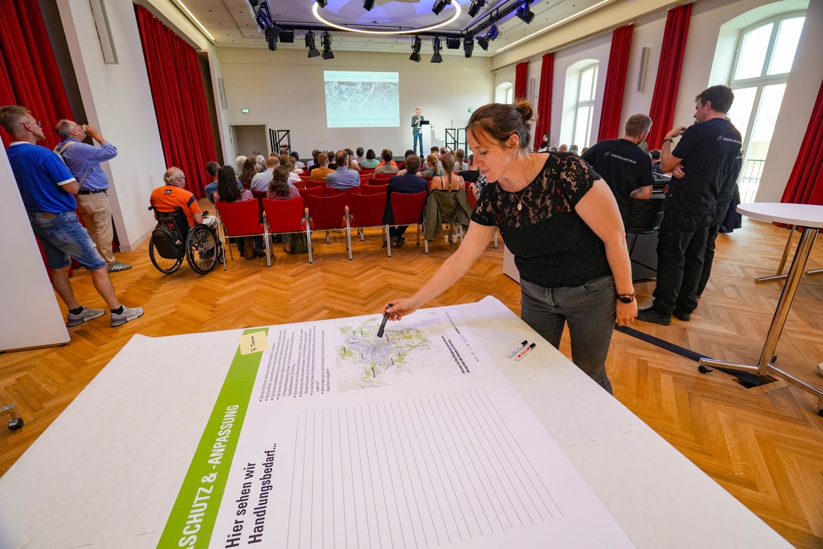 Eine Veranstaltung im Balkonsaal des Friedrichsforums. Im Vordergrund deutet eine Person mit einem Stift auf eine Karte. Foto: Stadt Bayreuth