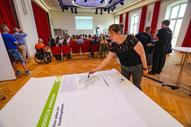 Eine Veranstaltung im Balkonsaal des Friedrichsforums. Im Vordergrund deutet eine Person mit einem Stift auf eine Karte. Foto: Stadt Bayreuth