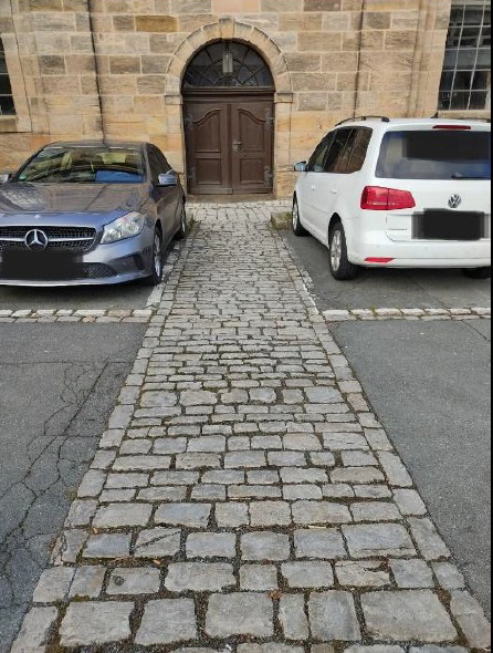 Zwei Autos stehen auf Parkplätzen vor dem Hintereingang der Ordenskirche.