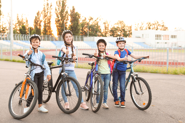 Kinder mit Fahrradhelmen und Fahrrädern lächeln in die Kamera