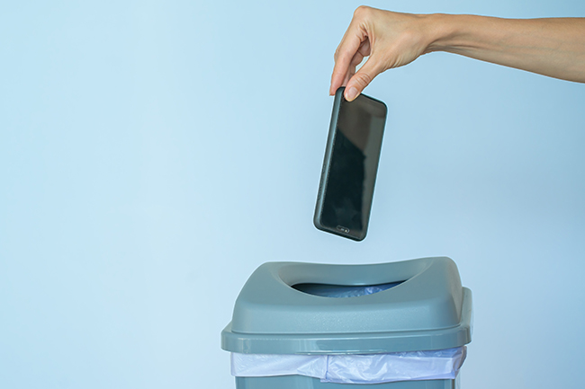 Eine Frau wirft ein Handy in einen Mülleimer